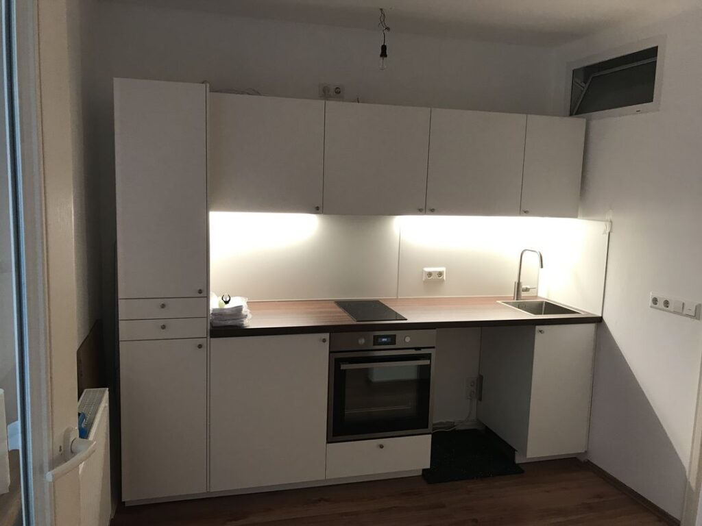 Moderne weiße Einbauküche mit Ofen und Spüle.